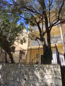 a house with a fence and a tree in front of it at Guest House Jelena in Budva