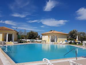a large swimming pool with chairs and a house at Iliaktida Studio-Villas in Lefkada Town
