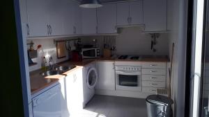 a kitchen with white cabinets and a washer and sink at Casa Férias Melides in Melides