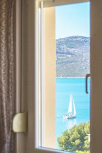 a window with a sail boat in the water at Apartment Punta in Seget Vranjica