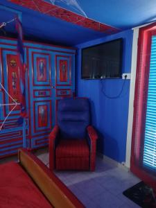niebieski pokój z czerwonym krzesłem i telewizorem w obiekcie Affitto breve Spider-man house w Katanii