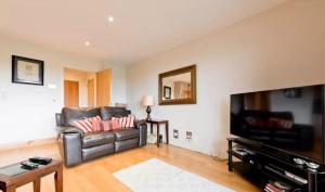 sala de estar con sofá de cuero y TV de pantalla plana en Dublin Corporate Apartment en Lucan