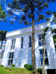 ein weißes Haus mit Bäumen davor in der Unterkunft Piavi Residencial in São Francisco de Paula