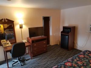 a hotel room with a desk and a bedroom at Budget Host Inn in Bedford