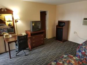 a hotel room with a bed and a desk and a television at Budget Host Inn in Bedford