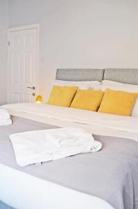 uma cama com lençóis brancos e almofadas amarelas em Northwood Park East em Stoke-on-Trent