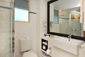a bathroom with a toilet, sink, mirror and bath tub at Comfort Inn & Apartments Northgate Airport Motel in Brisbane
