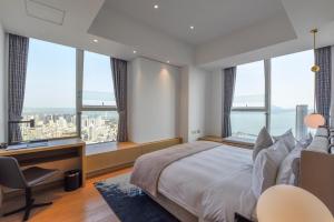 a bedroom with a bed and a desk and windows at The Clouds Apartment in Shenzhen