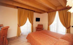 a bedroom with a bed and a chair and windows at Hotel Garnì Il Giglio in Commezzadura