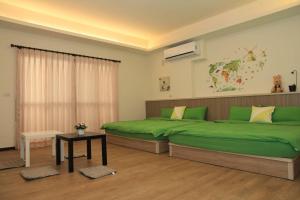 a bedroom with two green beds and a table at Ann Home in Magong