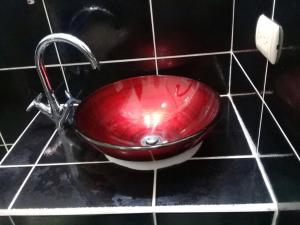 un lavandino rosso in un bagno con un rubinetto di Apartamentos del Puerto a Tela