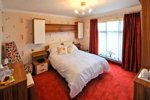 Un dormitorio con una gran cama blanca y una ventana en Englewood Lodge, en Douglas