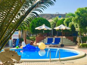 a resort swimming pool with a toy pig and chairs at Hotel Casa Playa Zorritos in Zorritos
