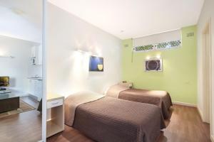 a hotel room with two beds and a mirror at Ultimate Apartments Bondi Beach in Sydney