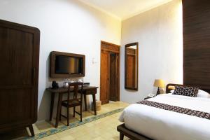 a bedroom with a bed and a desk and a tv at Joglo Mandapa Boutique Hotel in Yogyakarta