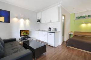 a living room with a couch and a bed and a kitchen at Ultimate Apartments Bondi Beach in Sydney