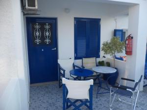 a room with two tables and chairs and a blue door at Marina's Studios Serifos in Livadi