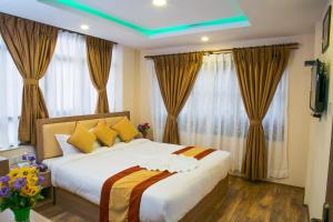 1 dormitorio con 1 cama blanca grande con almohadas amarillas en Sakura Boutique Hotel, en Katmandú