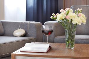 a vase of flowers and a glass of wine on a table at Glas-Hotel 3* in Żary