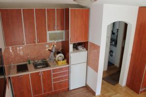 Elle comprend une petite cuisine avec des placards en bois et un évier. dans l'établissement Calm Apartment, à Belgrade