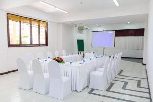 una sala conferenze con tavoli e sedie bianchi e schermo di Lazi Beach Resort a La Gi Altre 26 foto