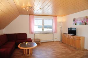 sala de estar con sofá, mesa y TV en Ferienwohnungen Lindlhof, en Riedenburg