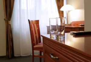 a desk with two glasses on top of a dresser at Hotel Grand in Nové Zámky