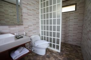 a bathroom with a white toilet and a sink at The Onsen Hot Spring Resort in Batu