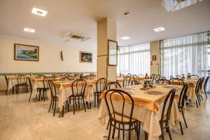 a dining room with tables and chairs and windows at Hotel Tiziana in Rimini