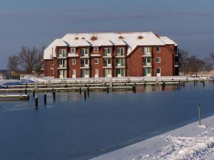 um edifício com neve sobre ele ao lado de um corpo de água em Lagunenstadt Ueckermünde AG em Ueckermünde