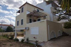 uma grande casa branca com garagem em Elena's House em Artemida