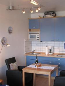 シュレースヴィヒにあるFerienwohnung Schlosserのキッチン(青いキャビネット、ワイン1本付きのテーブル付)