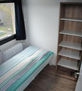 a small bedroom with a bed and a book shelf at Ferienwohnung Homeyer in Schilksee