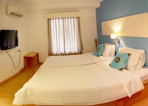 Cette chambre comprend un grand lit blanc et une télévision. dans l'établissement Nantra de Comfort, à Bangkok