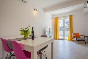 a kitchen with pink chairs and a table with a wine glass at Apartment Garden breeze in Cres
