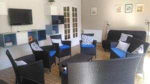 a living room with chairs and a couch and a tv at Au cèdre bleu in Saint-Martin-Boulogne