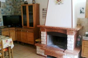 a living room with a brick fireplace with a tv at La Mia Casa Sulla Collina in Valsinni