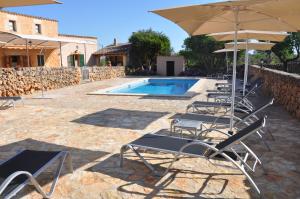 a group of chairs and umbrellas next to a pool at Can Porretí Agroturisme in Lloret de Vistalegre