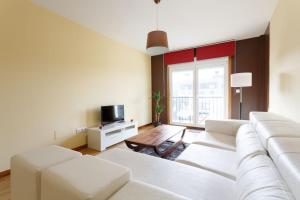 a living room with a white couch and a tv at 1- Apartamento Playa Canido in Malpica