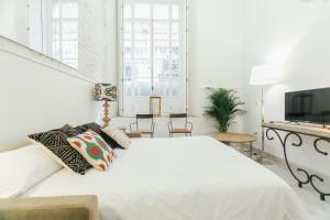 a white bedroom with a large bed and a television at CSE Pajaritos in Seville