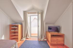 コスタ・ノヴァにあるCasa Do Bicoのベッドルーム(ベッド1台、ドレッサー、テレビ付)