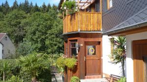a house with a wooden door and a balcony at Hammerfinken-Nest in Wurzbach