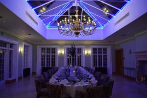 a large room with a table with chairs and a chandelier at Willington Hall Hotel in Tarporley