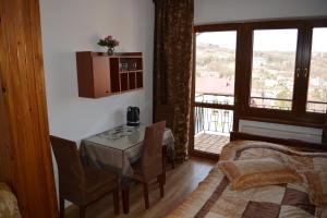 a room with a table and chairs and a window at Pokoje Gościnne BARTEK in Iwonicz-Zdrój