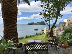a table and chairs sitting next to the ocean at A Villa by the Sea Bed & Breakfast in Vila Franca do Campo