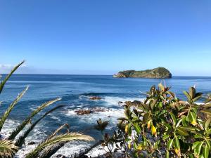 vista sull'oceano con un'isola in lontananza di A Villa by the Sea Bed & Breakfast a Vila Franca do Campo