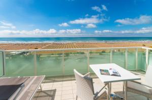 a balcony with a table and chairs and the beach at Hotel Montecarlo in Bibione