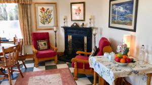 een woonkamer met een tafel en stoelen en een open haard bij Carraig-Mor House Bed & Breakfast in Toormore
