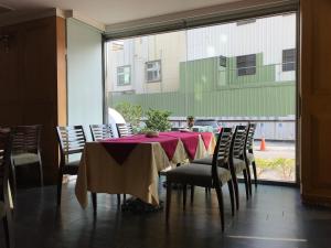 虎尾镇什叶派伊赫酒店的一间有桌子、椅子和窗户的餐厅