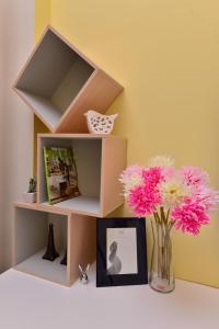 a shelf with a vase of pink flowers and a picture at STSP Guest House in Xinshi